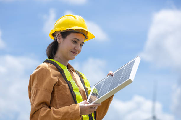 istock Female engineer ecology solar panel plant environment electricity. Alternative innovation energy. woman holding solar panel wind turbines in background. 2182104397
