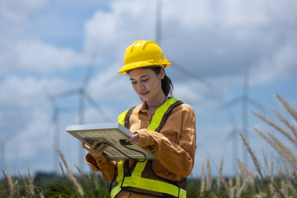 istock Female engineer ecology solar panel plant environment electricity. Alternative innovation energy. woman holding solar panel wind turbines in background. 2182104423