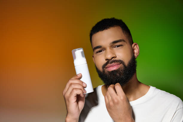 A young man applies skincare while smiling, surrounded by colorful lighting and tranquility.