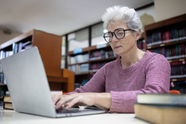 istock Senior Woman Typing on a Laptop in a Library, 2182115361
