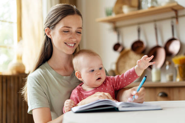 istock Mother holding baby while writing in notebook at home 2182118584