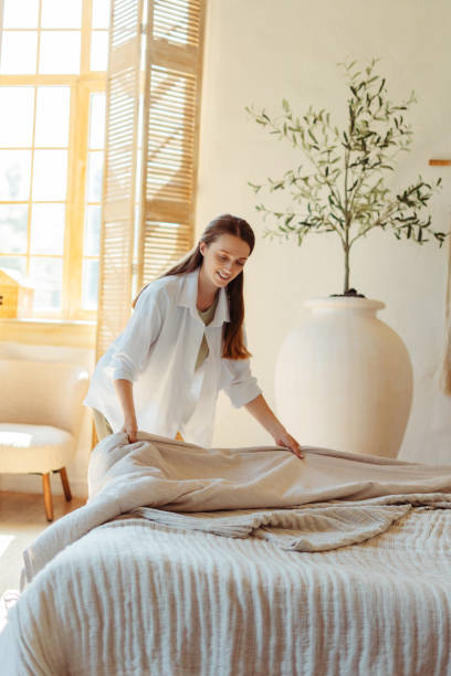 istock Housekeeper making bed in hotel room or airbnb apartment 2182118927