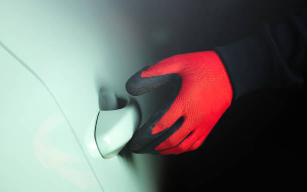 istock Man's gloved hand holding a screwdriver, attempting to pry open a car door handle. The image represents the concept of car theft, highlighting the risk and importance of vehicle security 2182119686