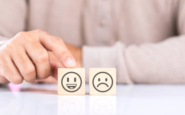 istock A man choosing between a happy and sad face on wooden blocks, ultimately selecting the happy one. The concept of starting each day with positivity, emphasizing the importance of a bright outlook 2182119998