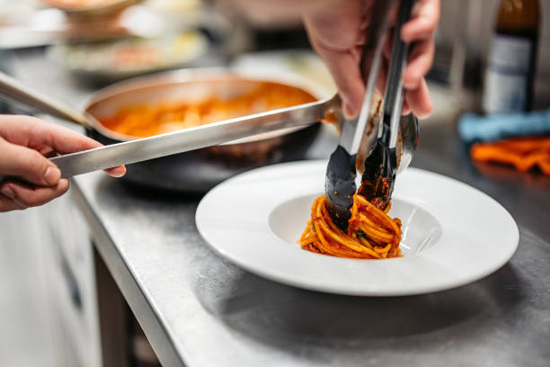 Young Chef Making Bolognese Pasta In A Commercial Kitchen