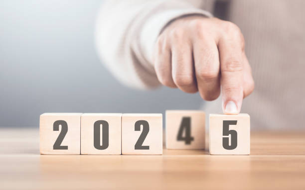 istock Hand replaces 2024 with 2025 using number blocks, symbolizing the transition into the new year, representing change, progress, and the ongoing passage of time 2182120229