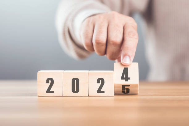 istock Hand replaces 2024 with 2025 using number blocks, symbolizing the transition into the new year, representing change, progress, and the ongoing passage of time 2182120233