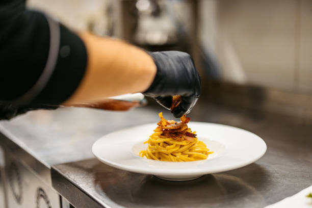 istock Young Chef Garnishing Pasta Carbonara In A Commercial Kitchen 2182121319