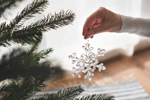 istock Woman decorates a Christmas tree with a glass, handmade snowflake 2182125336