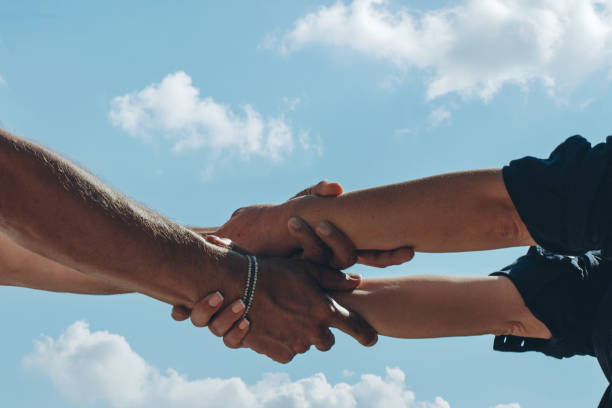 A medium, low-angle view shot of an unrecognisable multi-ethnic homosexual couple joining hands.