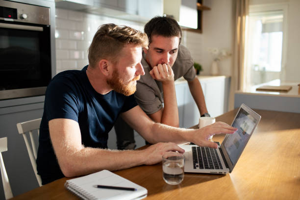 istock Young male couple using a laptop at home 2182128207
