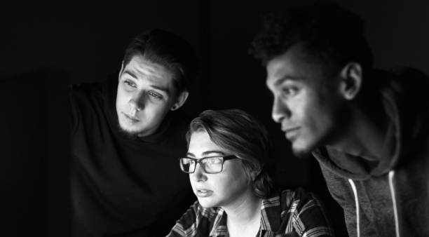istock Three young people concentrating on a computer, reflected in the woman's glasses 2182133170
