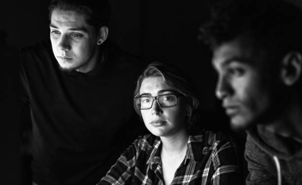 Young people at a computer, reflected in the woman's glasses as she looks up at the camera
