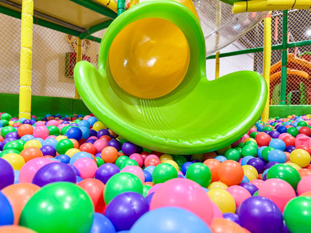 This image captures a vibrant indoor playground featuring a rainbow slide surrounded by an ocean of colorful balls.