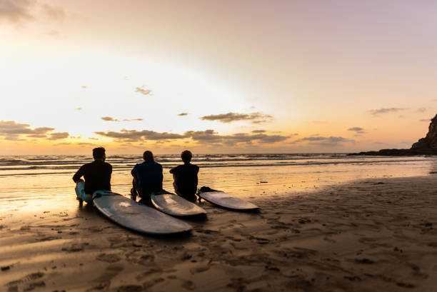 surfer friends talking on the beach - surfer stockfoto's en -beelden