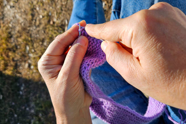 istock Close-up of hands knitting with purple wool and needles 2182138903