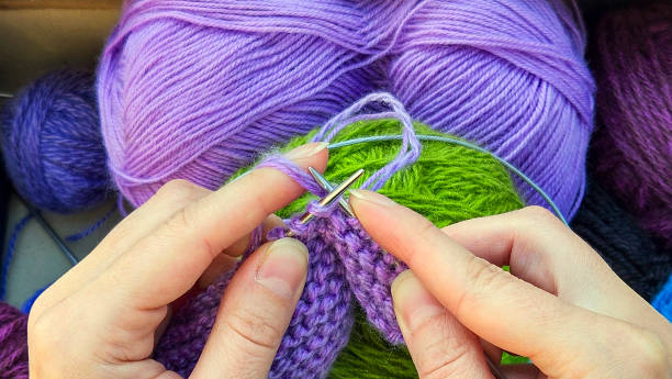 istock Close-up of hands knitting with purple wool and needles 2182138909