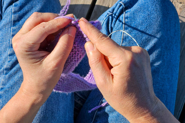 istock Close-up of hands knitting with purple wool and needles 2182138920