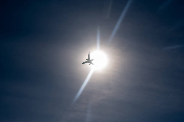 An airplane from below with lots of sky and bright sun