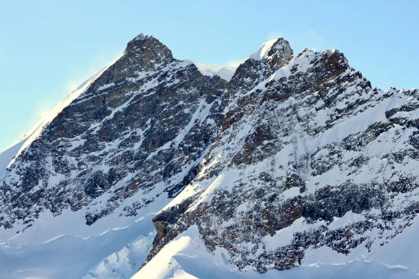 WS Bernese Alps peaks with cornice in the saddle against blue sky, Switzerland.