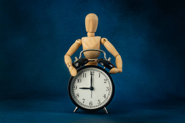istock Conceptual photo. Wooden man hugging alarm clock. 2182145185
