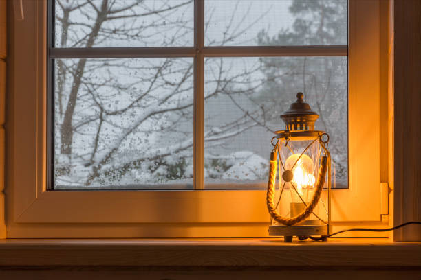 Lamp lantern on the windowsill, winter snowy landscape outside the window.