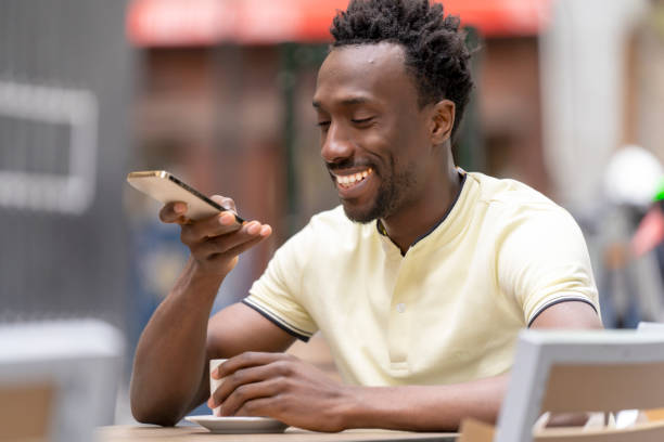 istock Man talking on smartphone, smiling, holding coffee, relaxing at an outdoor cafe table. 2182148173
