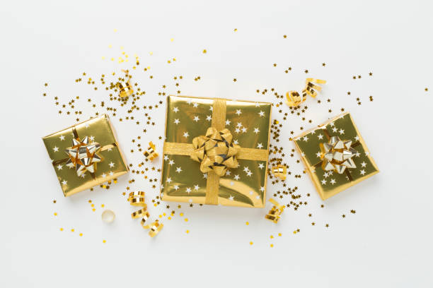 istock Golden gift boxes and confetti on color background, top view 2182155263