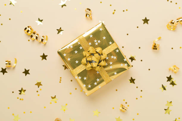 istock Golden gift boxes and confetti on color background, top view 2182155269