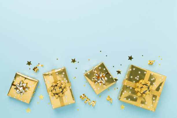 istock Golden gift boxes and confetti on color background, top view 2182155274