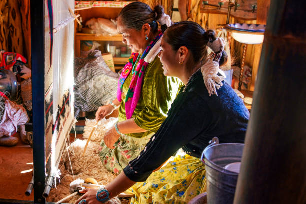 istock Traditional Elderly Navajo Woman Working to Make an Authentic Blanket on a Loom, Teaching Her Granddaughter and Spending Quality Time in a Traditional Navajo Hogan in Monument Valley Southern Utah, Northern Arizona 2182159295