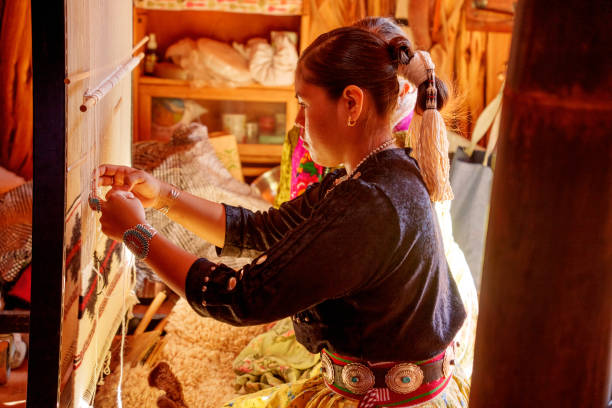 istock Traditional Elderly Navajo Woman Working to Make an Authentic Blanket on a Loom, Teaching Her Granddaughter and Spending Quality Time in a Traditional Navajo Hogan in Monument Valley Southern Utah, Northern Arizona 2182159359