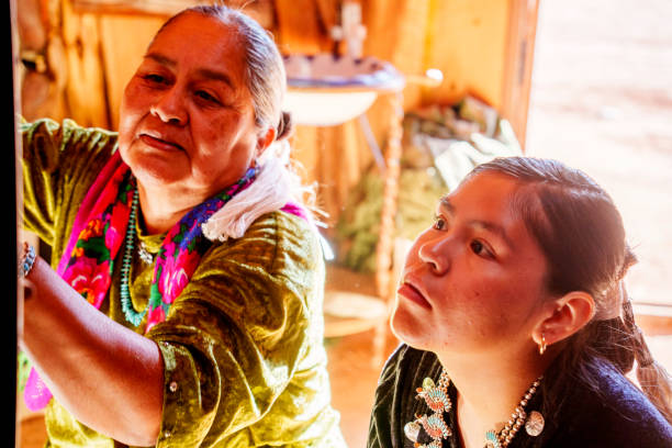 istock Traditional Elderly Navajo Woman Working to Make an Authentic Blanket on a Loom, Teaching Her Granddaughter and Spending Quality Time in a Traditional Navajo Hogan in Monument Valley Southern Utah, Northern Arizona 2182159401