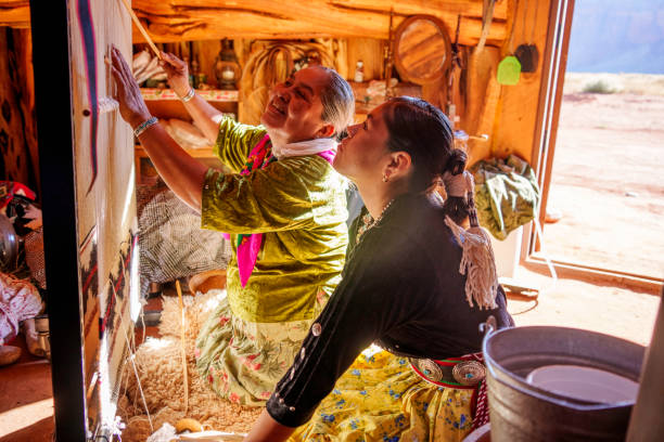 istock Traditional Elderly Navajo Woman Working to Make an Authentic Blanket on a Loom, Teaching Her Granddaughter and Spending Quality Time in a Traditional Navajo Hogan in Monument Valley Southern Utah, Northern Arizona 2182159455