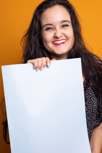 istock Woman holding a blank poster smiling and looking at camera. 2182162104