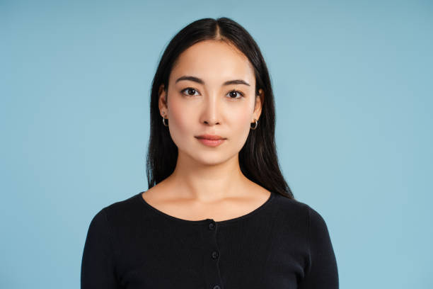 Attractive, asian woman looking at camera posing on a blue background