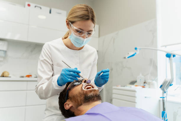 istock Dentist performing teeth whitening procedure on male patient 2182170203