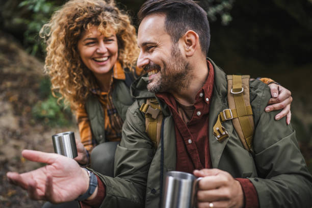 istock husband and wife hikers sit in front cave and drink from metal mug 2182171302