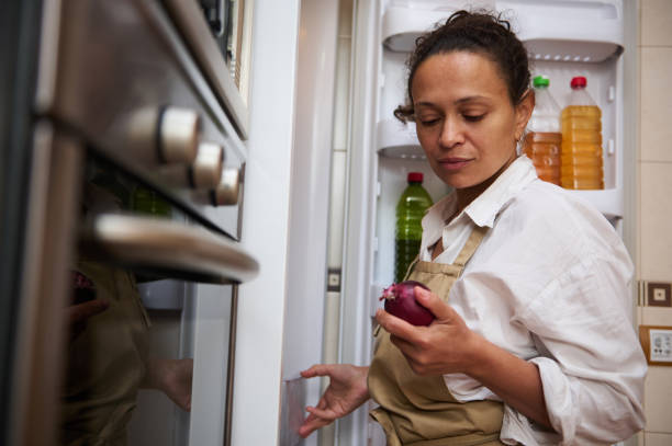 istock Woman examining a red onion in front of an open fridge 2182171338