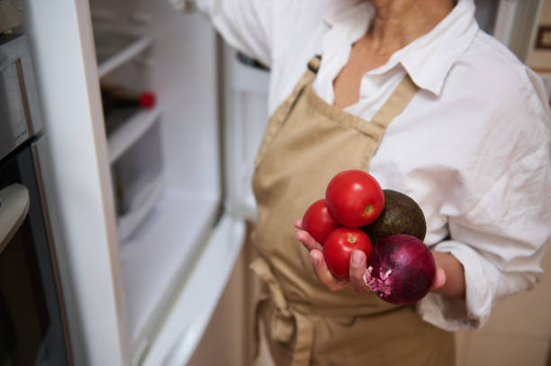istock Person in apron holding fresh tomatoes, avocado, and onion 2182171343