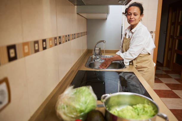 istock Woman washing hands in kitchen preparing fresh meal 2182171377
