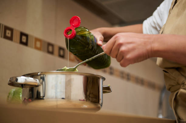 A close-up of a person pouring olive oil into a pot, preparing a nutritious meal. The image conveys culinary skills, health, and home cooking in a modern kitchen setting.