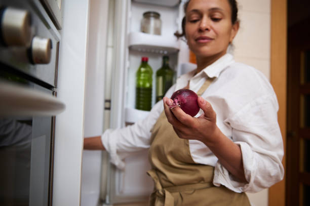 istock Woman holding red onion in modern kitchen setting 2182171571