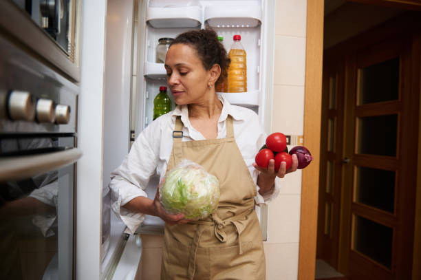istock Woman wearing apron sorting vegetables from refrigerator 2182171576