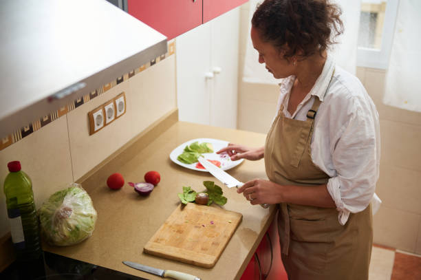 istock Woman preparing fresh salad in a home kitchen setting 2182171679