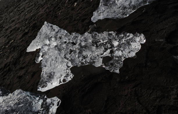 Ice chunks melting slowly on a black sand beach, creating a beautiful contrast of light and dark