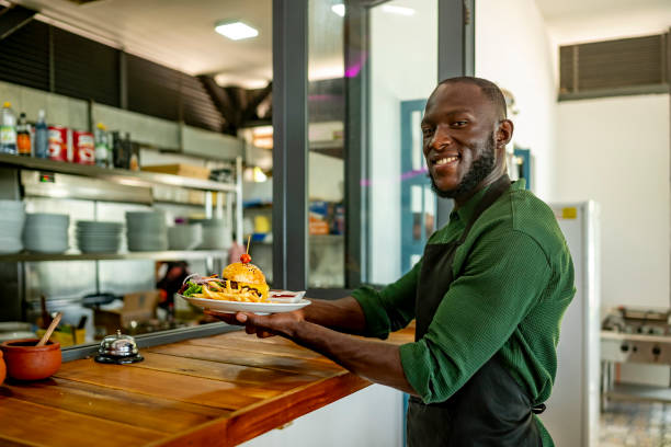 istock Smiling Chef Serving Delicious Burger at Restaurant 2182188192