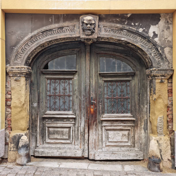 Old wooden door with stucco decoration and a head sculpture above the entrance