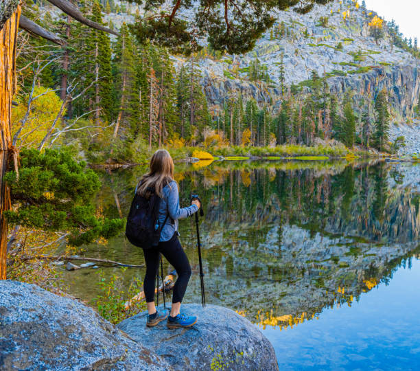 Female Hiker on The Shore of Eagle Lake With Fall Color and Mountain Reflection , Desolation Wilderness National Forest, California, USA