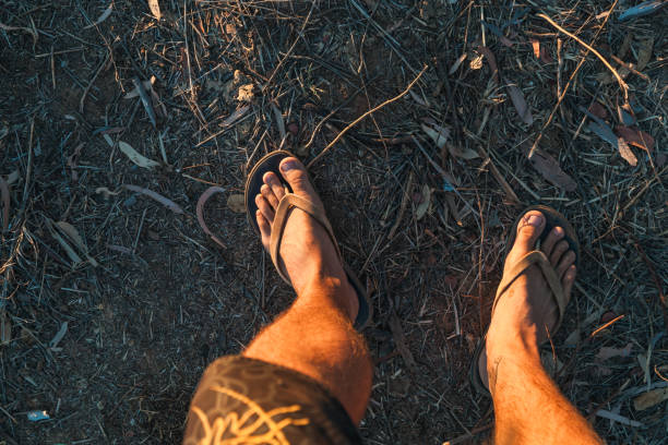 Enjoying the rugged terrain of Gibb River Road in Western Australia, a traveler strolls barefoot in flip-flops, experiencing the natural beauty and vibrant surroundings on a sunny day.